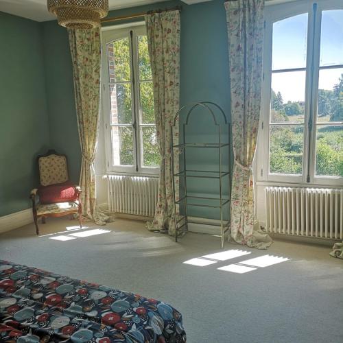 a bedroom with a bed and a chair and windows at Maison de maître sur grand terrain in Mézilles