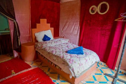 a bedroom with a bed with blue pillows on it at Sahara Garden Luxury Camp in Merzouga