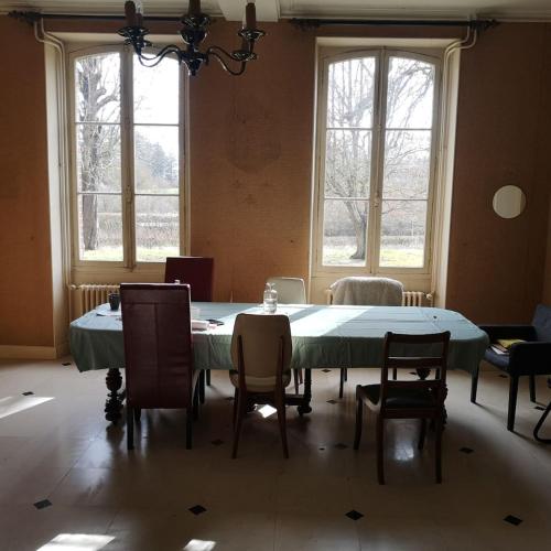 une salle à manger avec une table, des chaises et des fenêtres dans l'établissement Maison de maître sur grand terrain, à Mézilles