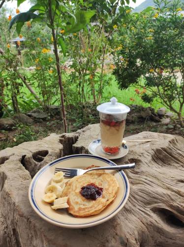 a plate of pancakes and a drink on a tree stump at Little House in KhauPha, Mu Cang Chai - homestay, cuisine, cafe in Mù Cang Chải