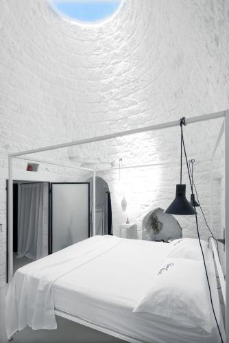 a white bedroom with a large white bed with a black lamp at Cocotrullo in Cisternino