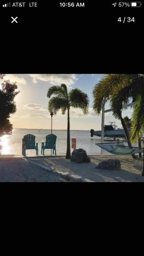 two chairs and palm trees on a beach with the ocean at Keys Paradise! in Key Largo