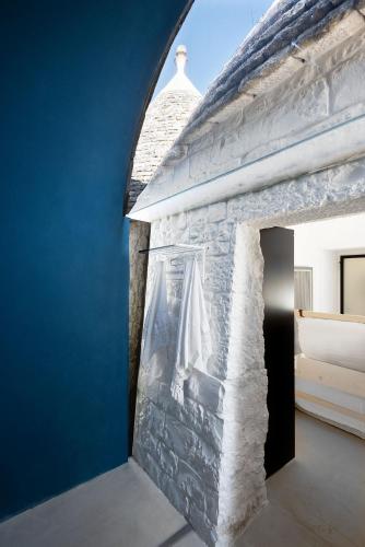 a stone fireplace in a bedroom with a blue wall at Cocotrullo in Cisternino