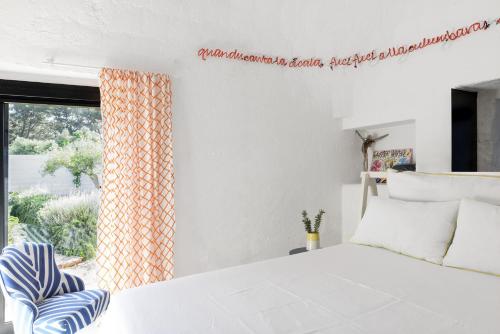 a bedroom with a white bed and a window at Cocotrullo in Cisternino