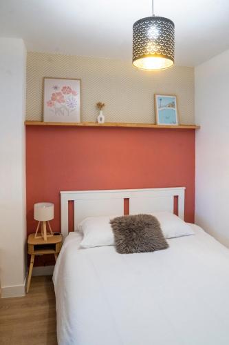 une chambre avec un lit blanc avec un mur rouge dans l'établissement Appartement sur les quais, à Caen