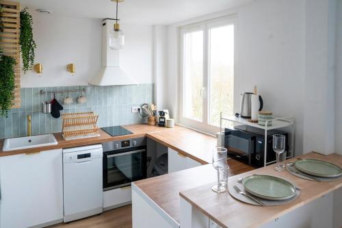 une cuisine avec des armoires blanches et un comptoir en bois dans l'établissement Appartement sur les quais, à Caen