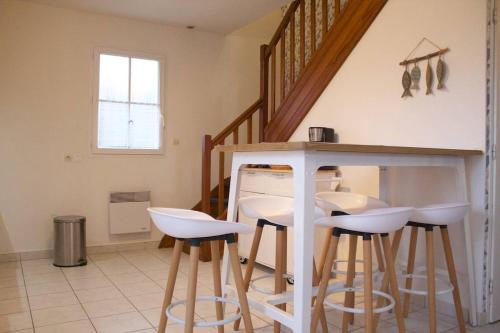 une cuisine avec des tabourets blancs sous un escalier dans l'établissement Mais 3 pièces 4 couchages SAINT GEORGES D'OLERON SGO000-083, à Saint-Georges-dʼOléron