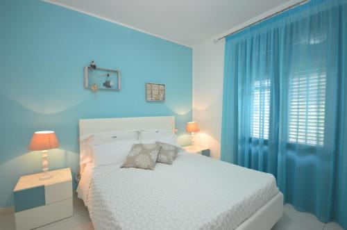 a bedroom with a white bed and blue walls at Le Stelle Sea Rooms in San Vito lo Capo