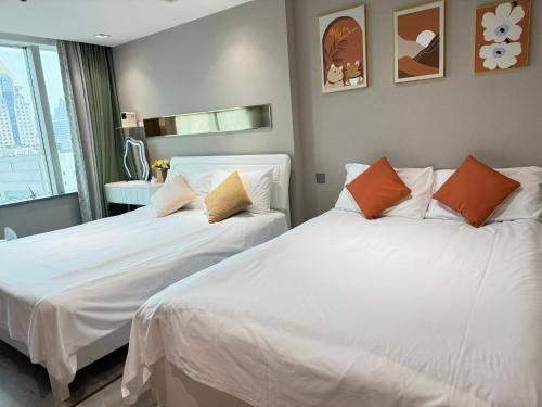 two beds in a room with white sheets and orange pillows at Today Aparthotel West Lujiazui Shanghai in Shanghai