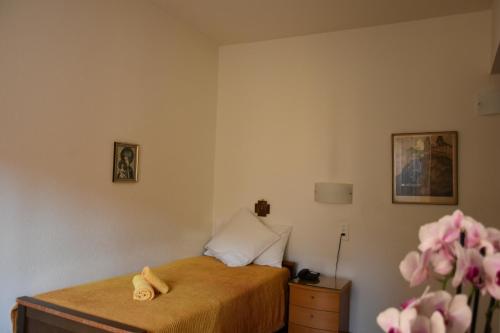 a bedroom with a bed and a dresser and flowers at Casa Santa Birgitta in Lugano