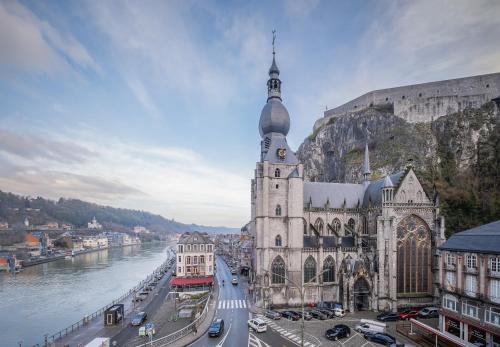 a large building with a clock tower next to a river at NOMAD APARTMENTS - Côté Meuse in Dinant