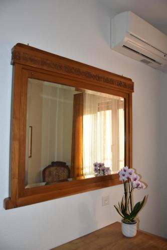a mirror with a wooden frame and a vase of flowers at Casa Santa Birgitta in Lugano