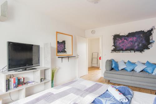 a living room with a couch and a flat screen tv at - Stellar Haven Deluxe with Cosmic Design - 3-Room Space-Themed Apartment 75 qm - Central Location - Balcony - Renovated 2024 with TV & Netflix - Full Kitchen - Free Parking - Near Metro & Airport - Galaxy-Inspired Interior - in Duisburg