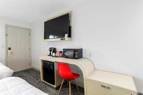 a room with a red chair and a desk with a microwave at Signature Inn Berkeley in Berkeley
