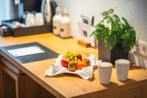a plate of fruit on a desk with two cups at Hotel Artist in Biel
