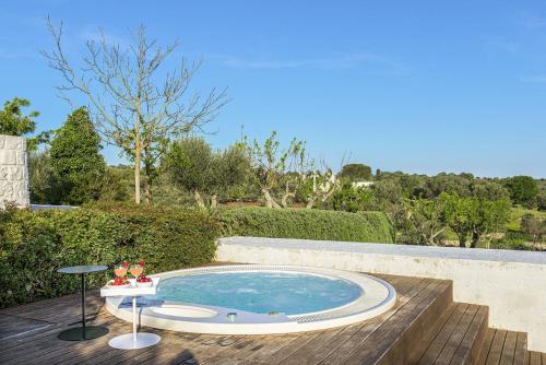 a small swimming pool on a deck with a table at Cocotrullo in Cisternino