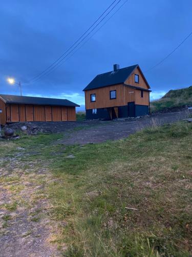 a barn and a house in a field at House Nordkapp Fishing Adventure in Sarnes