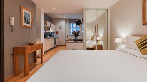 a bedroom with a large white bed and a kitchen at Cannon Street Serviced Apartments by LovelyStay in London