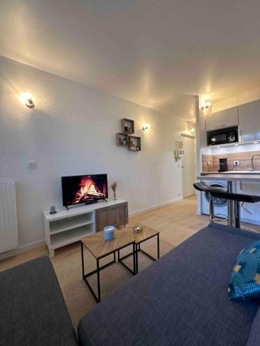 un salon avec un canapé et une télévision sur un mur dans l'établissement Studio neuf tout équipé - Calme - Proche centre ville - Parking gratuit, à Longjumeau