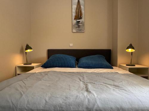 a bedroom with a bed with blue pillows and two lamps at Cecilia's cozy apartment in Athens