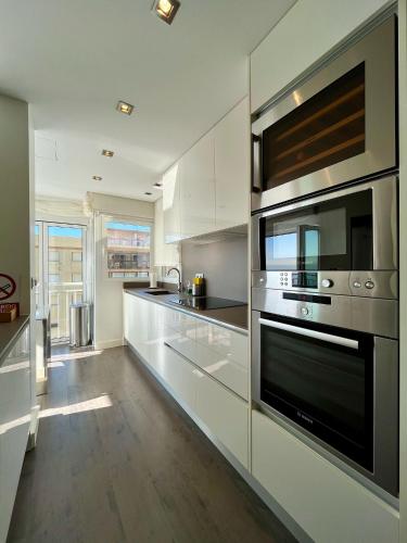 a kitchen with white cabinets and stainless steel appliances at El Horizonte de Benicassim III, Descubre esta lujosa propiedad a los pies del Mediterraneo in Benicàssim