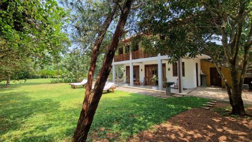 a house with a yard with a bench and trees at Villa Arana Bentota in Bentota