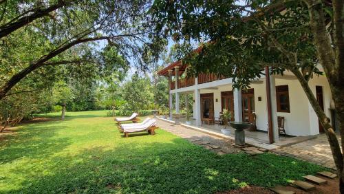 a house with a bench in the yard at Villa Arana Bentota in Bentota