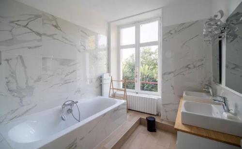 La salle de bains blanche est pourvue d'une baignoire et de deux lavabos. dans l'établissement Villa spacieuse avec piscine à Saint-Gence, à Saint-Gence
