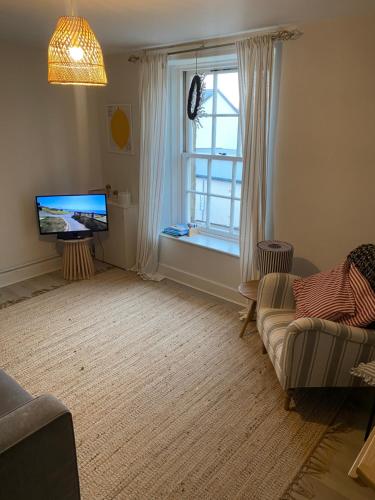 a living room with a couch and a tv and a window at Neuk Nest,serene 2 bedroom apartment in Anstruther in Anstruther