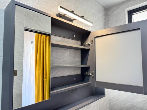 内罗毕Sunset Cosy abode的浴室里一面镜子,一面有黄色窗帘