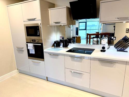 a kitchen with white cabinets and a counter top at Luxe Cardiff Centre Apartment Free Parking in Cardiff