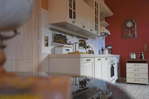 a kitchen with red walls and white cabinets at Villa Sophia in Karavostamo