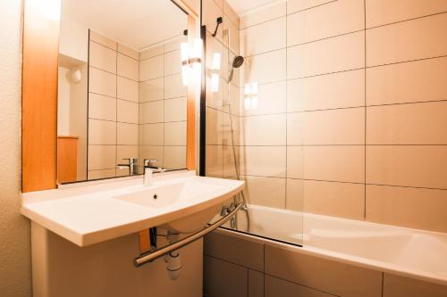 a bathroom with a sink and a mirror and a tub at easyHotel Nice Old Town in Nice