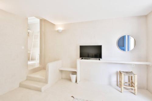 a white living room with a tv and a mirror at Baba Houlakia in Houlakia