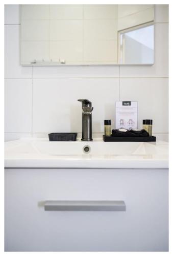 - un comptoir de cuisine blanc avec un évier et un miroir dans l'établissement Maison d artiste proche de Paris, à Alfortville