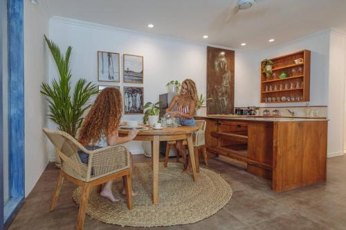 two women sitting at a table in a kitchen at Ulus - Tropical 1 Bedroom Ocean View Apartment by Triang Villas in Tanah Lot