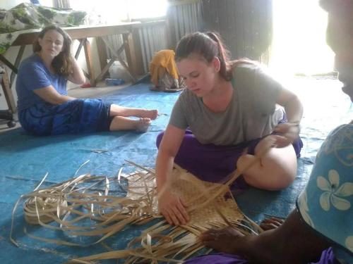 three women sitting on the floor working on a piece of wood at Village Life Experience - Naviti Island in Ngunu
