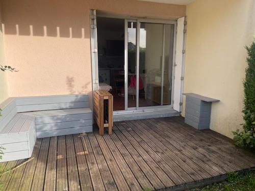 eine Veranda mit einer Bank und einer Glasschiebetür in der Unterkunft Un Cottage à la Mer in Le Pouliguen