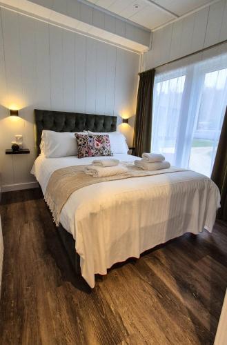a bedroom with a large bed and a large window at Loch Lomond Waterfront Luxury Lodges in Balmaha