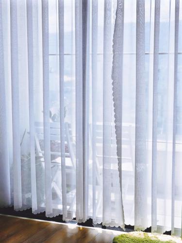 a window with white curtains in a room at Seafront Apartment TMS Quy Nhơn in Quy Nhon