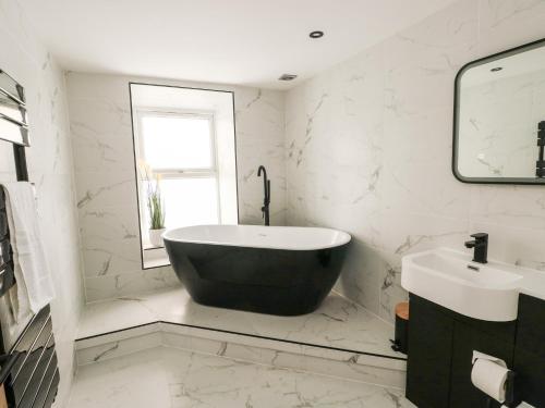 a bathroom with a black tub and a sink at 1 Mona Terrace in Holyhead