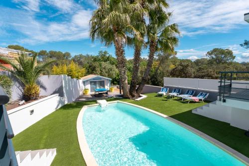 une cour avec une piscine et une pelouse bordée de palmiers dans l'établissement Villa Luxe & Éco -Rêve et Nature Pool et Spa, à Roquebrune-sur Argens