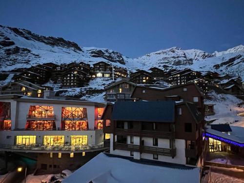 a large building with snow covered mountains in the background at Cime de Caron - Appartement cosy refait à neuf 4 personnes - Valthosun - Val Thorens in Val Thorens