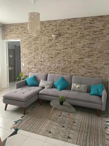 a living room with a couch and a brick wall at Appartement confortable avec vue sur mer à Le Robert in Le Robert