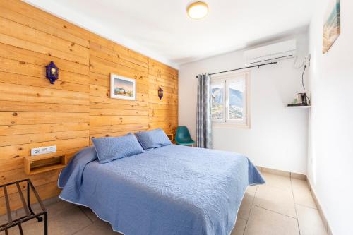 a bedroom with a bed and a wooden wall at Boutique Hotel El Olivar in Mojácar