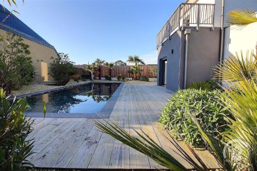 une piscine avec une terrasse en bois à côté d'une maison dans l'établissement Cocon maritime, à Gicquel