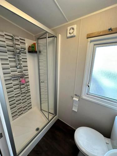 une salle de bain avec douche et toilettes et une fenêtre dans l'établissement Bungalow accueillant à Saint-Jean-de-Monts avec piscine, à Saint-Jean-de-Monts