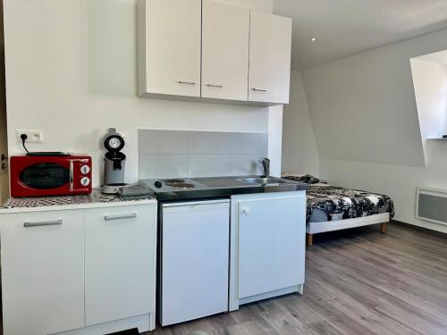 - une cuisine avec des placards blancs et un four micro-ondes rouge dans l'établissement #Petit cocon au cœur de Mulhouse, à Mulhouse