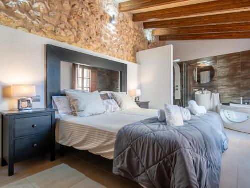 a bedroom with a large bed and a stone wall at Cas Mercader in Algaida