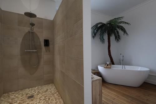La salle de bains est pourvue d'une baignoire et d'un palmier. dans l'établissement E Le clos des lumières, maison 13 pers avec jardin, à Épernay